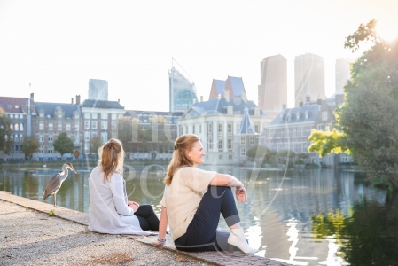 Vriendinnen zitten naast elkaar bij op Haagse Hofvijver bij zonsopkomst