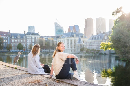 Vriendinnen zitten naast elkaar bij op Haagse Hofvijver bij zonsopkomst