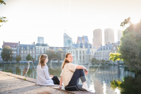 Vriendinnen zitten naast elkaar bij op Haagse Hofvijver bij zonsopkomst