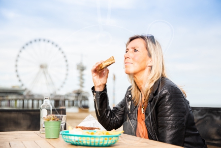 Vrouw eet een broodje op de boulevard