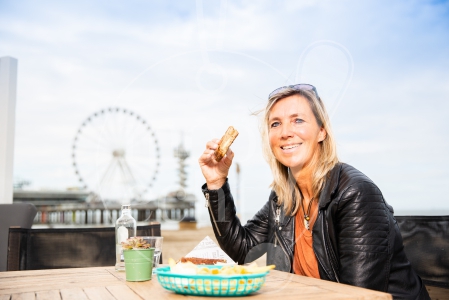 Vrouw eet een broodje op de boulevard