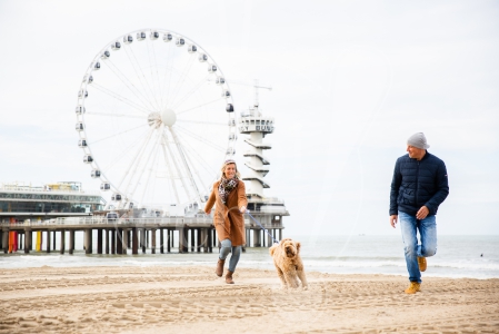 Stel rent samen over het strand met de hond op Scheveningen