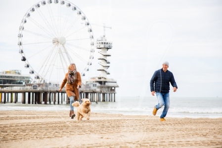 Stel rent samen over het strand met de hond op Scheveningen