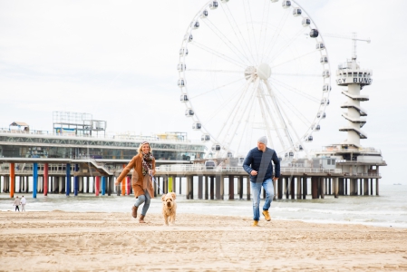 Stel rent samen over het strand met de hond op Scheveningen