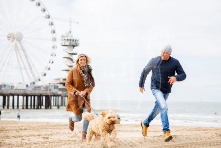 Stel rent samen over het strand met de hond op Scheveningen