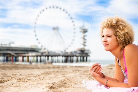 Meisje ligt op haar handdoek op Scheveningen met de Pier op de achtergrond