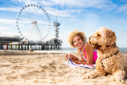 Meisje ligt op haar handdoek met haar hond op Scheveningen