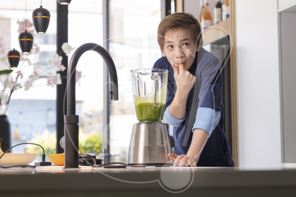 jongen pikt smoothie uit de keuken