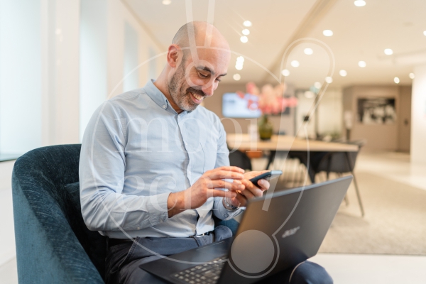 man aan het werk op zijn laptop en telefoon 1