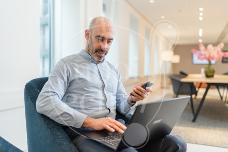 man aan het werk op zijn laptop en telefoon 2