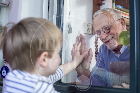 Jongetje en opa zien elkaar door raam tijdens Coronacrisis