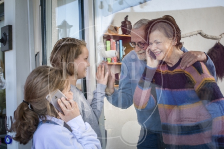 Kleinkinderen zwaaien naar en praten met opa en oma door raam