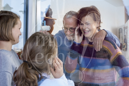 Kleinkinderen zwaaien naar en praten met opa en oma door raam