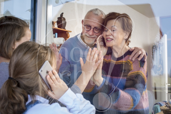 Kleinkinderen zwaaien naar en praten met opa en oma door raam