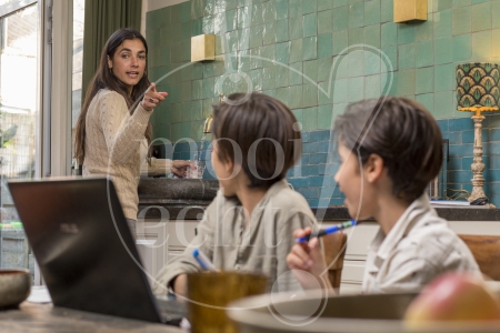 Twee jongens doen homeschooling met moeder in de keuken tijdens Coronacrisis